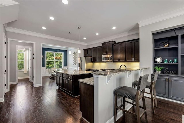 kitchen with appliances with stainless steel finishes, a center island, a breakfast bar, and recessed lighting