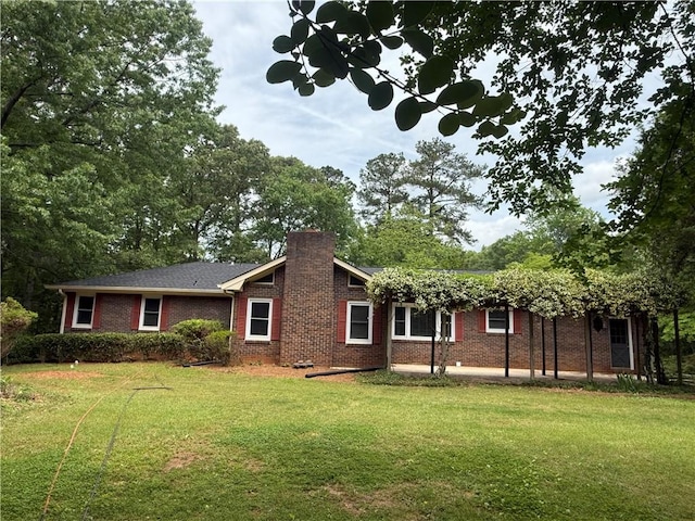 rear view of property with brick siding, a lawn, and a chimney