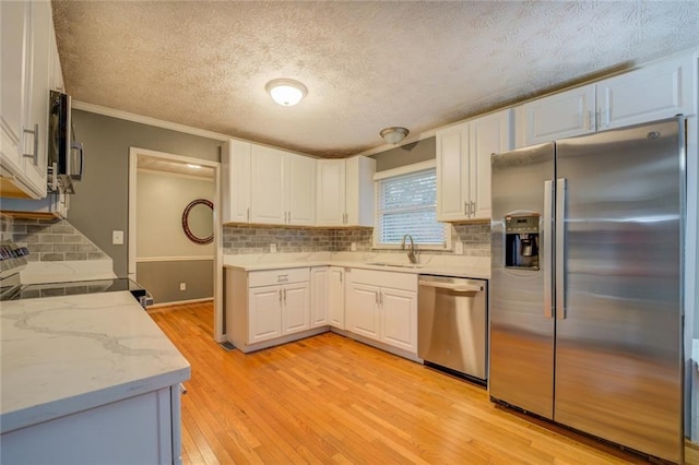 spare room featuring light wood finished floors, a chandelier, a textured ceiling, ornamental molding, and baseboards