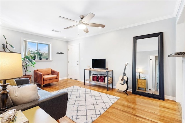living area featuring ceiling fan, wood finished floors, crown molding, and baseboards