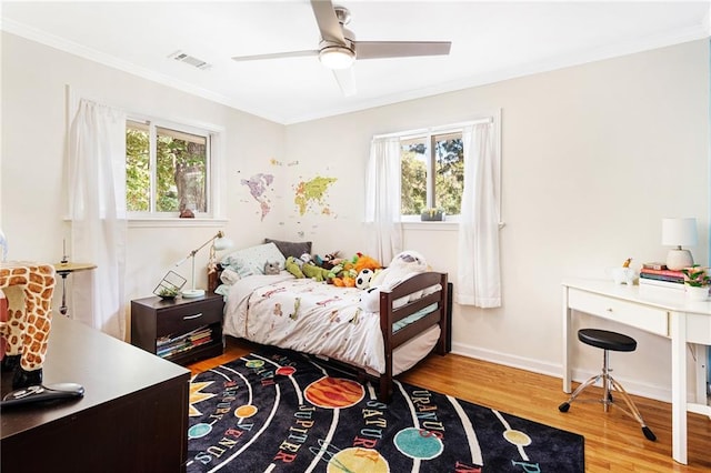 bedroom with wood finished floors, ornamental molding, an office area, baseboards, and a ceiling fan