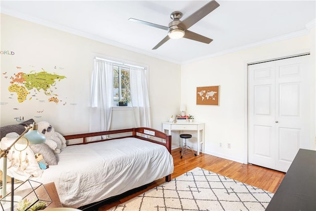 bedroom featuring crown molding, wood finished floors, baseboards, a closet, and a ceiling fan
