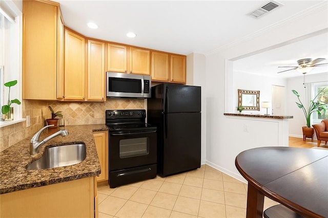 kitchen featuring black appliances, a sink, backsplash, baseboards, and dark stone counters