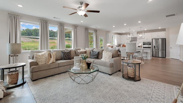 living room featuring recessed lighting, visible vents, and light wood finished floors