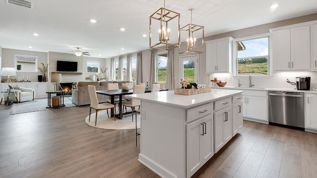 kitchen with a center island, visible vents, stainless steel dishwasher, a large fireplace, and a sink