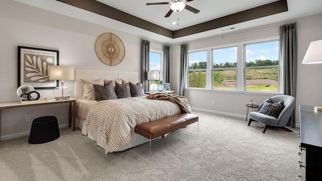 bedroom featuring baseboards, visible vents, a ceiling fan, a tray ceiling, and carpet floors