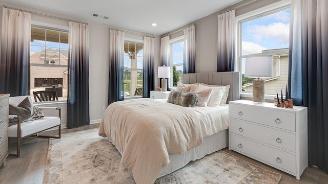 bedroom with light wood-type flooring, visible vents, and baseboards