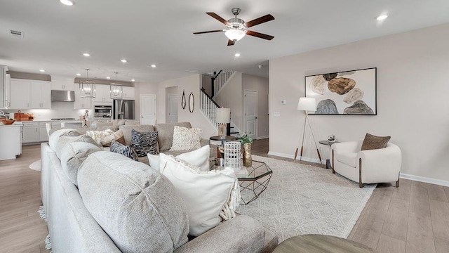 living area featuring light wood finished floors, recessed lighting, a ceiling fan, baseboards, and stairs