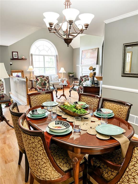 3809 Autumn View Ln NW, Acworth, GA 30101 - dining space with a chandelier, vaulted ceiling, light wood-style flooring, and crown molding