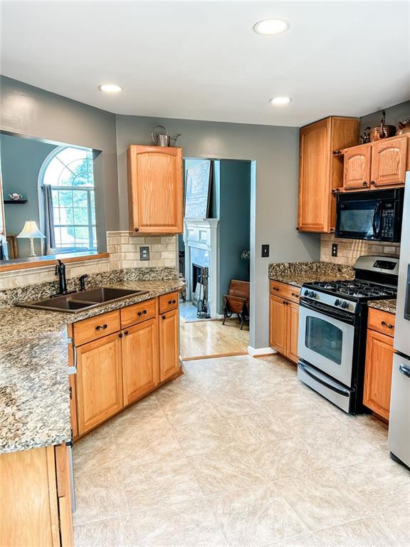 3809 Autumn View Ln NW, Acworth, GA 30101 - kitchen featuring stainless steel gas range, black microwave, tasteful backsplash, recessed lighting, and a fireplace
