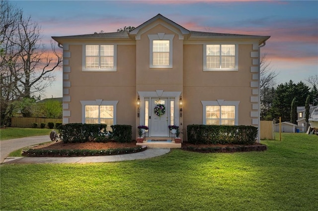 colonial inspired home featuring a front yard and stucco siding