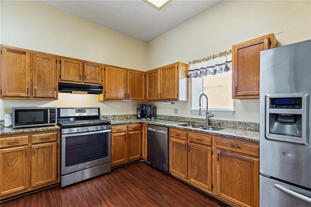 kitchen featuring a sink, stainless steel appliances, light stone counters, and under cabinet range hood