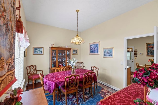 dining space featuring lofted ceiling, wood finished floors, and baseboards