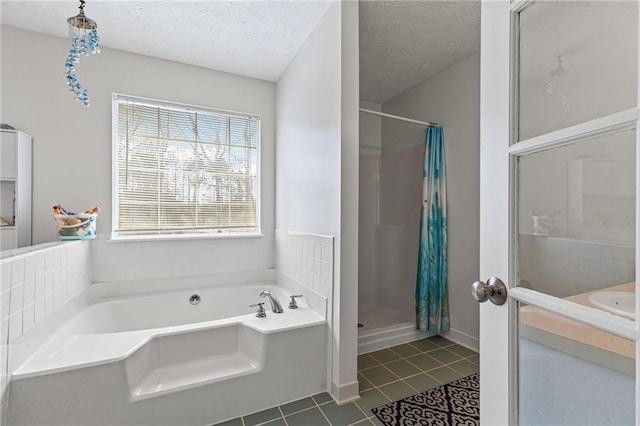 full bathroom featuring tile patterned floors, a bath, a stall shower, and a textured ceiling