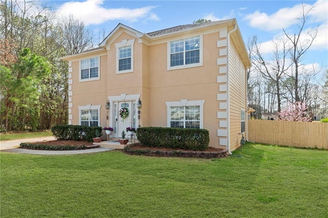 colonial home with stucco siding, a front lawn, and fence