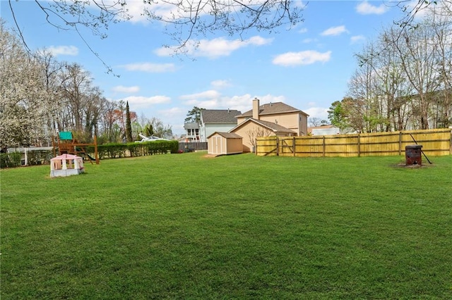 view of yard with an outbuilding, a playground, a fenced backyard, and a shed