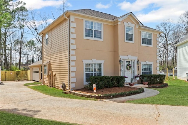 view of front facade with stucco siding, driveway, a front yard, and fence