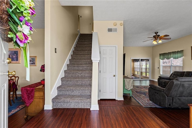 staircase with baseboards, wood finished floors, visible vents, and ceiling fan