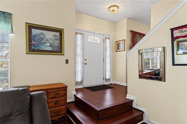 entryway with stairs, baseboards, a textured ceiling, and dark wood-style flooring