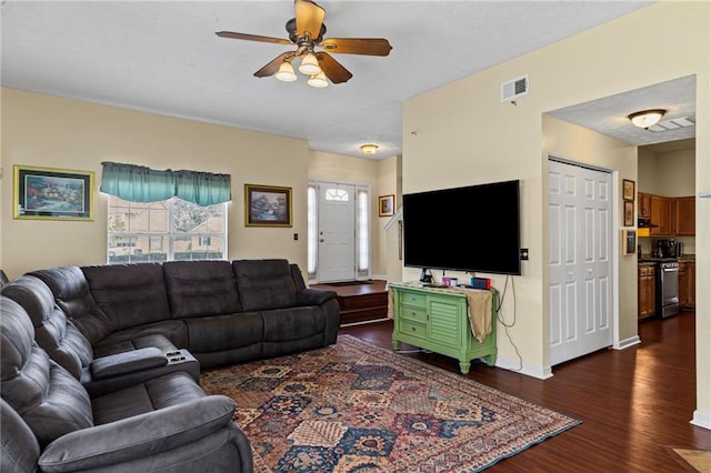 living room with visible vents, baseboards, dark wood-type flooring, and a ceiling fan