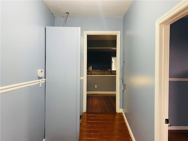 hallway featuring dark wood-style flooring and baseboards