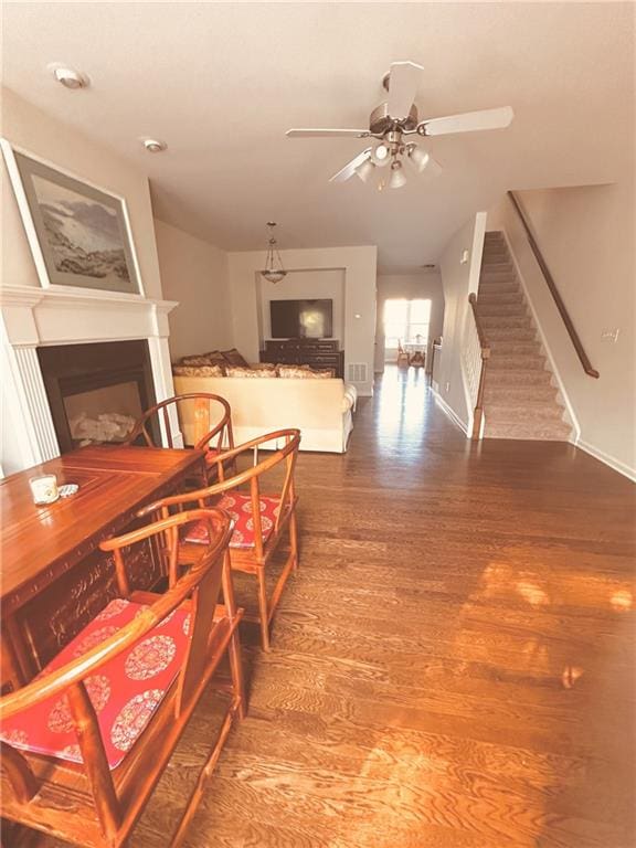 4438 Lassen Ct, Suwanee, GA 30024 - dining area featuring a fireplace, ceiling fan, wood finished floors, and stairway