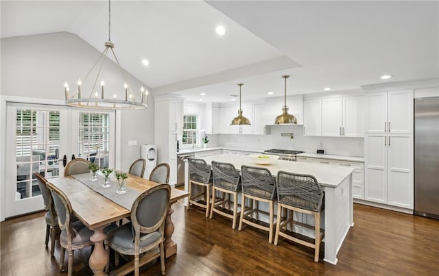 dining space featuring dark hardwood / wood-style floors, decorative columns, lofted ceiling, sink, and a notable chandelier