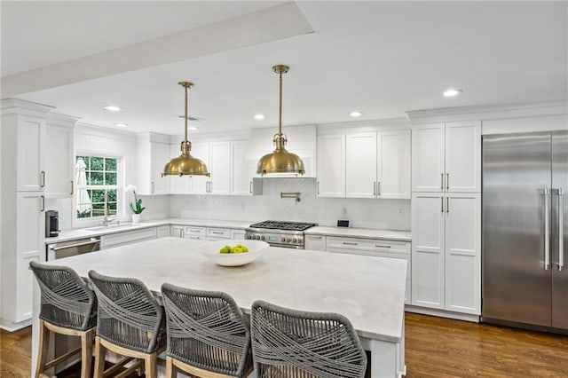 kitchen featuring white cabinetry, high end appliances, a breakfast bar area, and pendant lighting