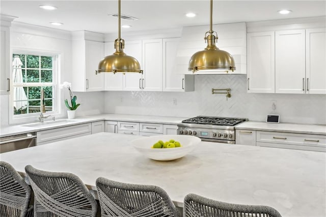 kitchen featuring stainless steel appliances, hanging light fixtures, white cabinets, and a kitchen bar