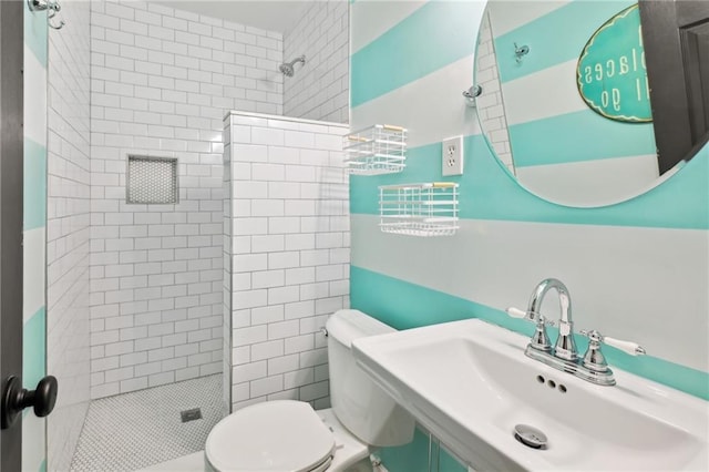 bathroom featuring toilet, sink, and a tile shower