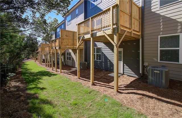 rear view of property featuring a yard, cooling unit, and a wooden deck