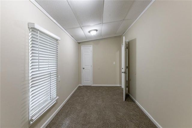 hallway with ornamental molding and dark colored carpet