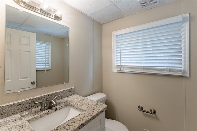 bathroom with toilet, a drop ceiling, and vanity