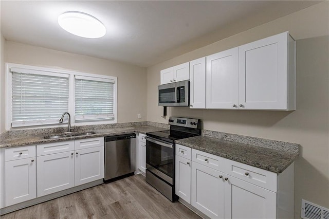 kitchen featuring appliances with stainless steel finishes, white cabinets, and light hardwood / wood-style floors