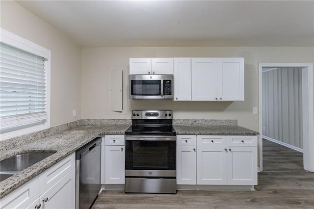 kitchen featuring white cabinetry, light stone counters, stainless steel appliances, and dark wood-type flooring