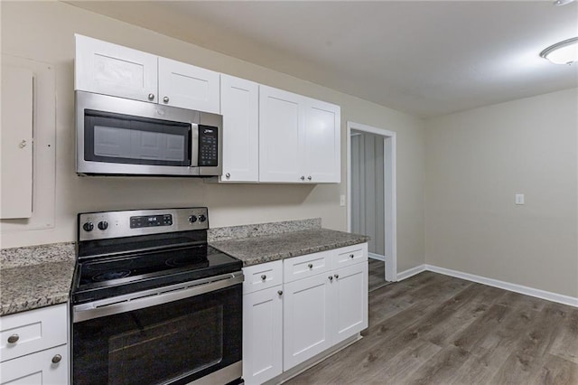 kitchen featuring appliances with stainless steel finishes, white cabinetry, dark stone counters, and dark hardwood / wood-style floors