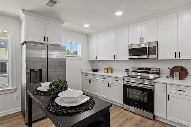 kitchen featuring stainless steel appliances, light countertops, visible vents, and white cabinets