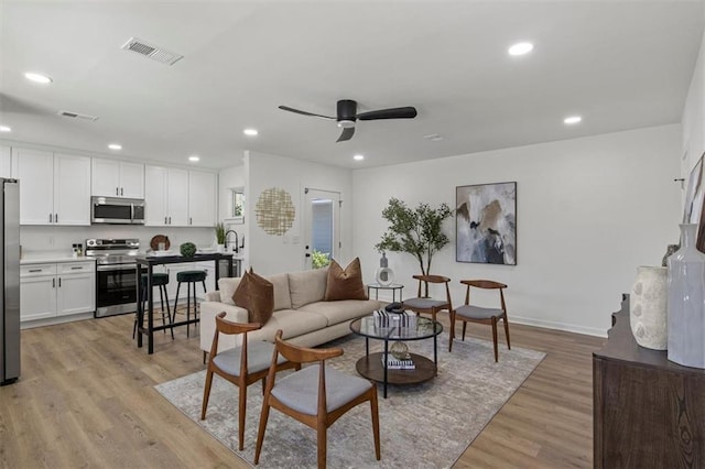 living room featuring ceiling fan, recessed lighting, light wood finished floors, and visible vents
