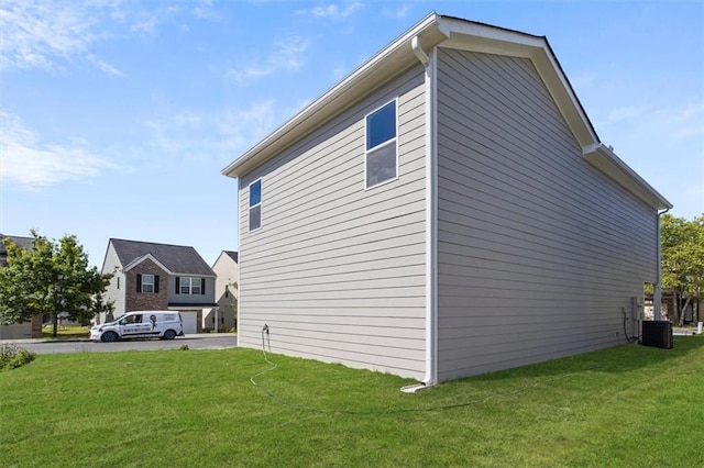 view of side of home featuring central air condition unit and a lawn