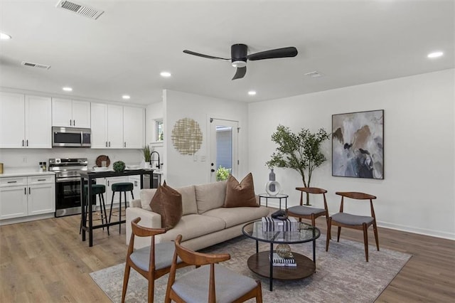 living area featuring ceiling fan, recessed lighting, visible vents, and light wood-style floors