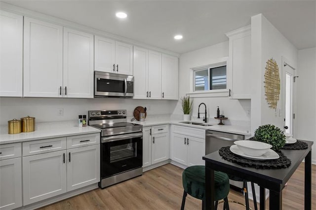 kitchen with white cabinetry, appliances with stainless steel finishes, light wood-style flooring, and a sink
