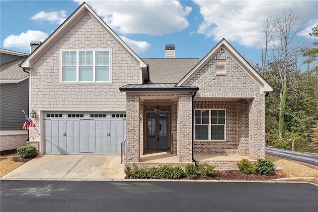 view of front of house featuring driveway, a standing seam roof, a garage, brick siding, and a chimney