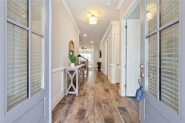 foyer entrance with a wainscoted wall, wood finished floors, stairway, crown molding, and a decorative wall