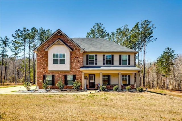 view of front of home with a front yard, covered porch, and brick siding