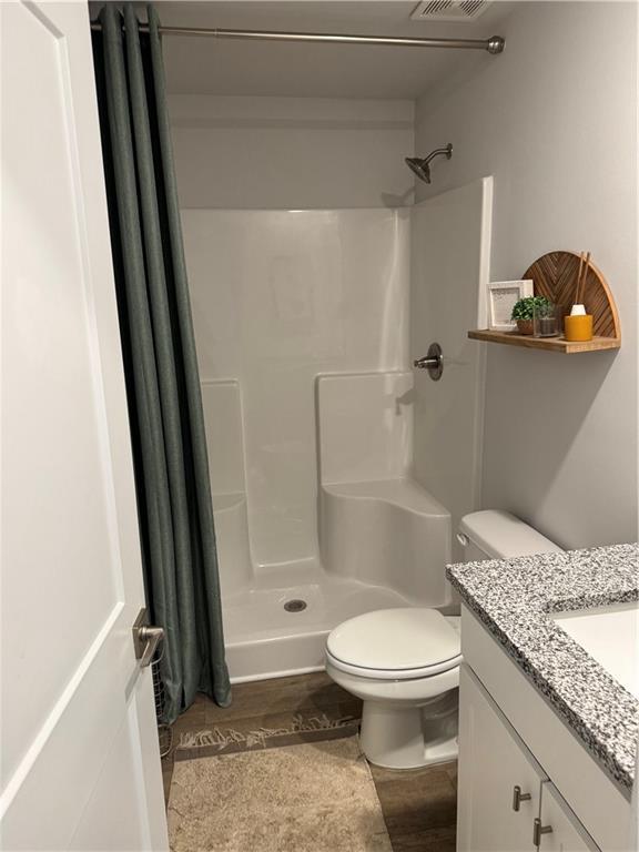 719 Windstream Dr, Lagrange, GA 30241 - bathroom featuring a stall shower, toilet, vanity, and wood finished floors