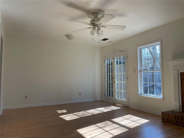 empty room with ceiling fan, wood finished floors, and baseboards