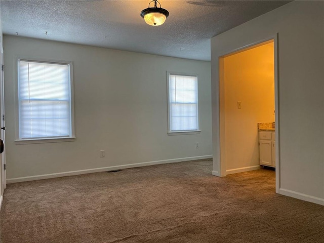 unfurnished bedroom featuring carpet, visible vents, baseboards, and a textured ceiling