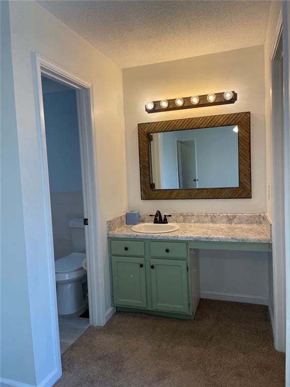 bathroom with carpet floors, toilet, vanity, a textured ceiling, and baseboards