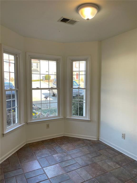 unfurnished room with baseboards, visible vents, and stone tile flooring