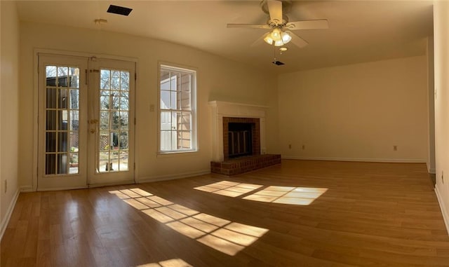 unfurnished living room featuring a fireplace, wood finished floors, a ceiling fan, and baseboards